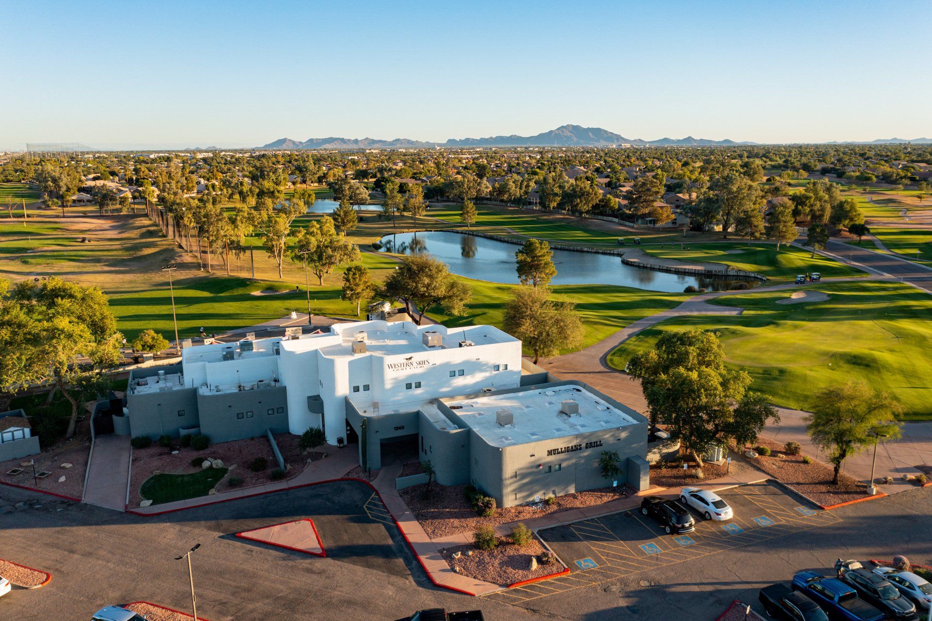 An aerial view of a golf course with a white building in the foreground.