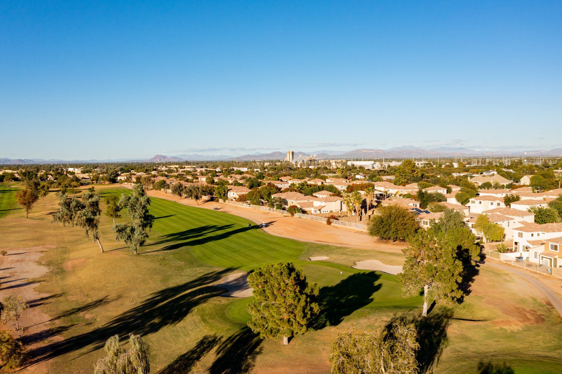An aerial view of a golf course with a city in the background.