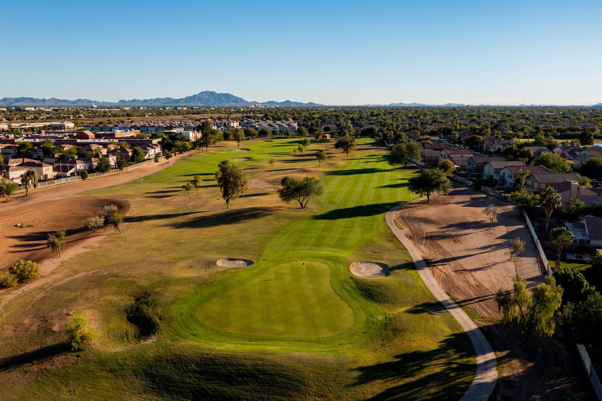 An aerial view of a golf course with a residential area in the background.