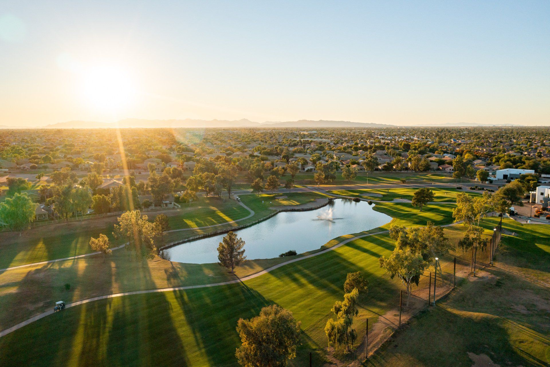 An aerial view of a golf course and a lake at sunset.
