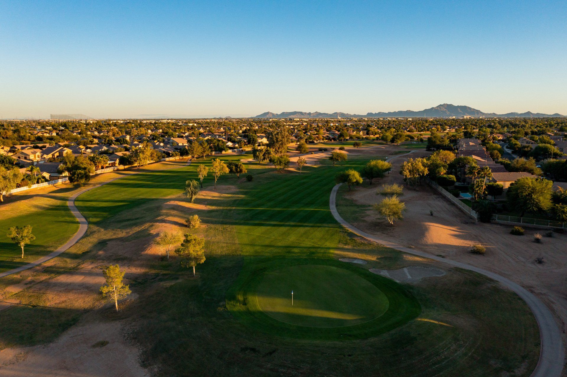 An aerial view of a golf course with a city in the background.