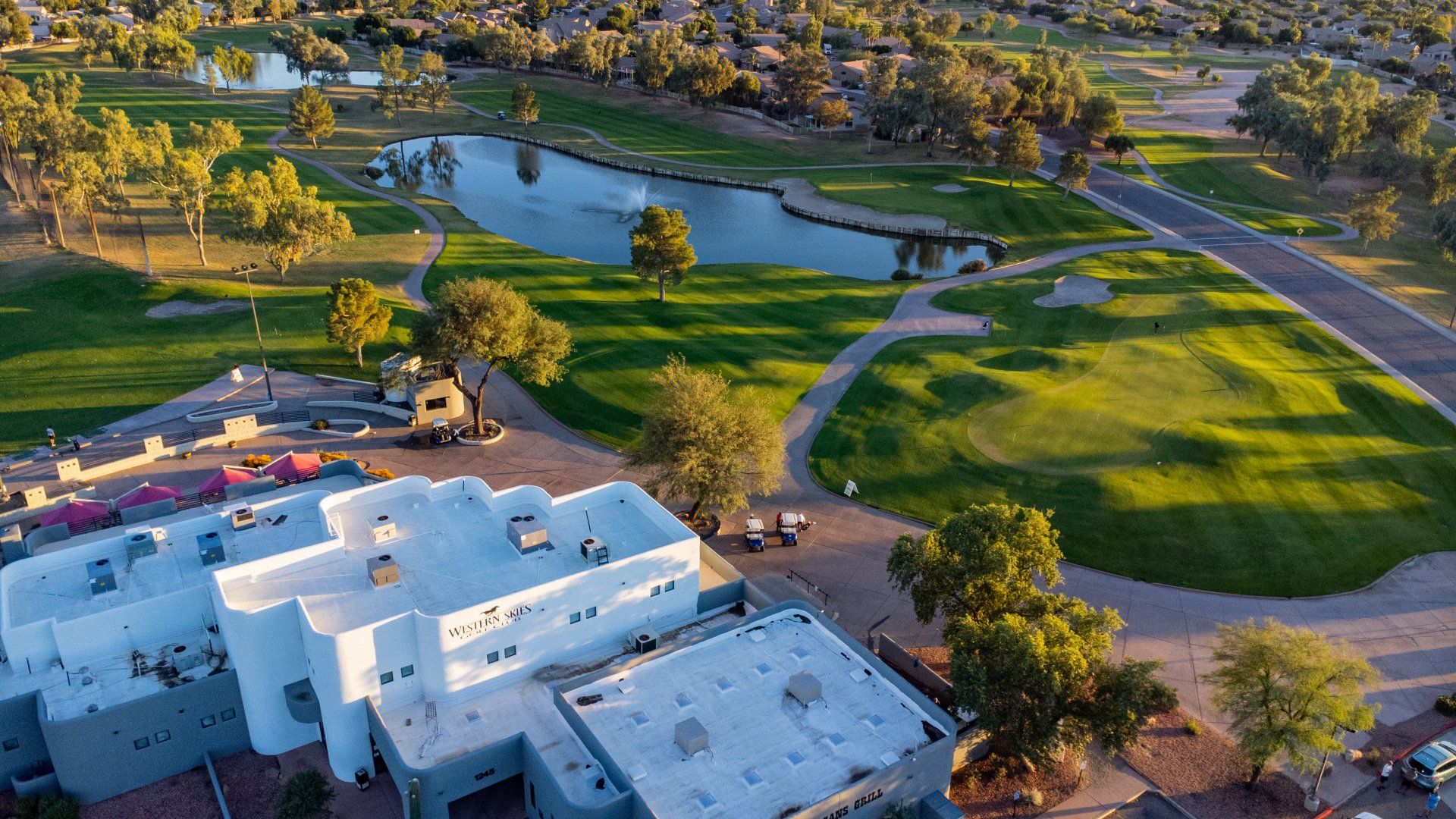 An aerial view of a golf course with a large building in the foreground.