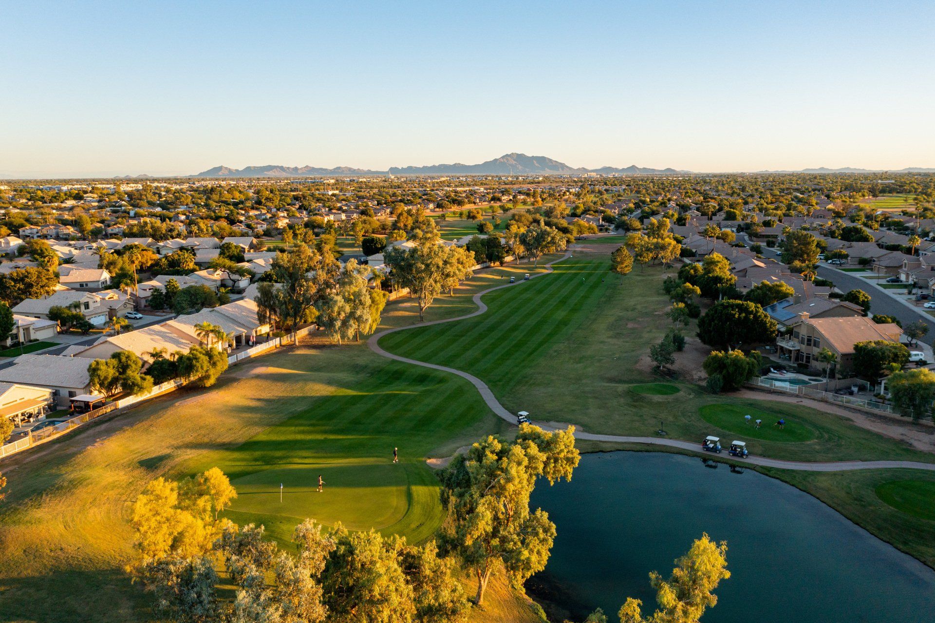An aerial view of a golf course surrounded by trees and a lake.