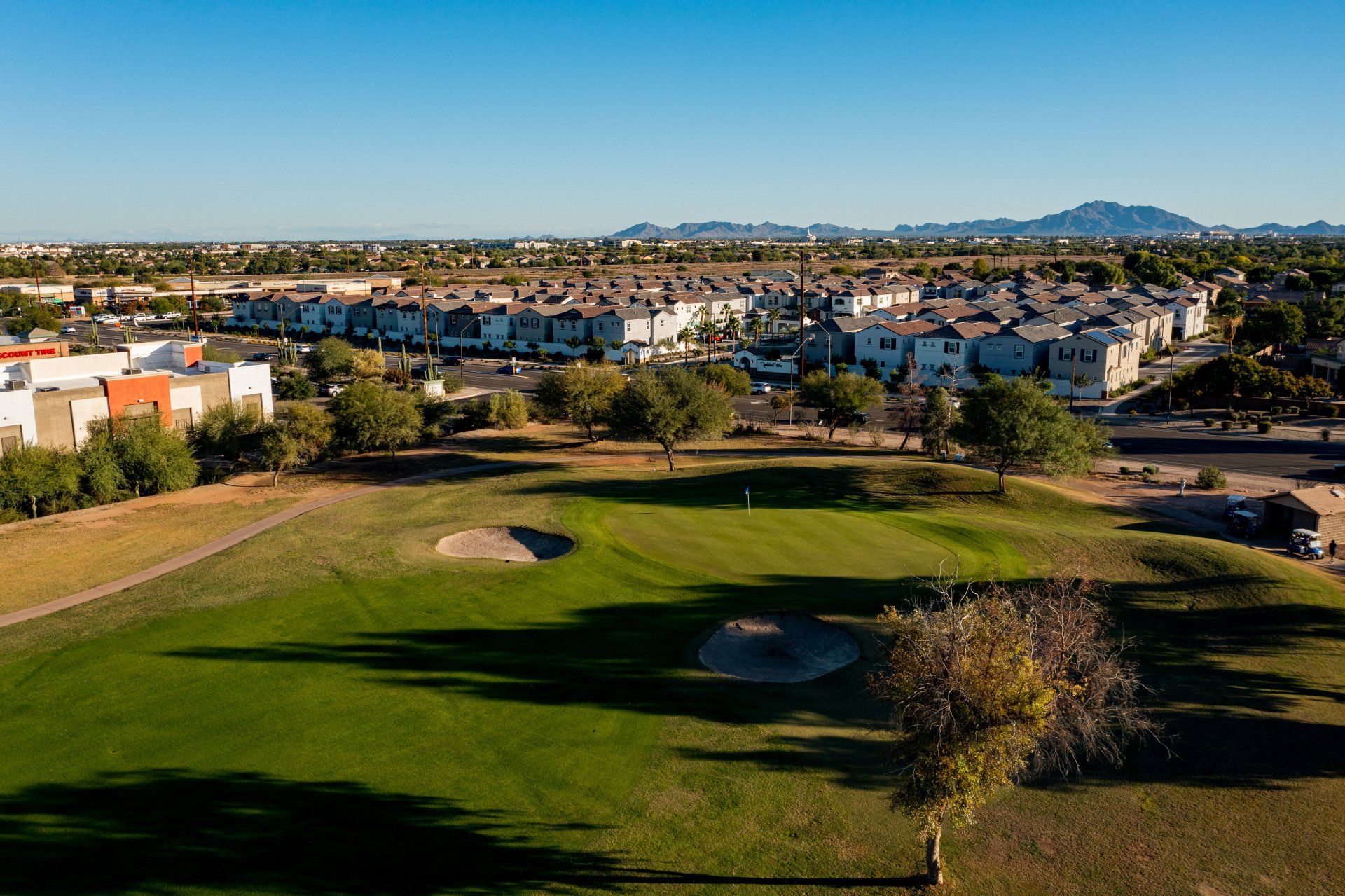 An aerial view of a golf course with houses in the background.