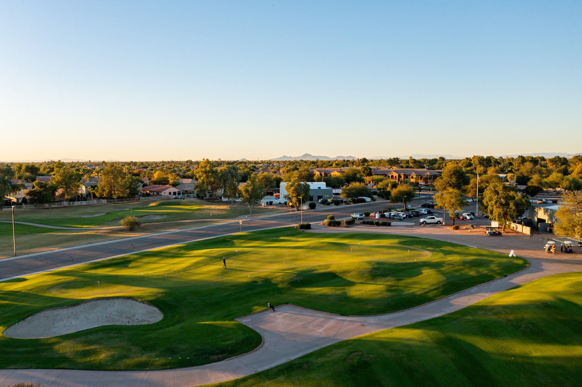An aerial view of a golf course with a city in the background.