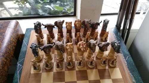 Chess set with animal-shaped pieces on a checkered board. The pieces include giraffe, elephant, and other animals.