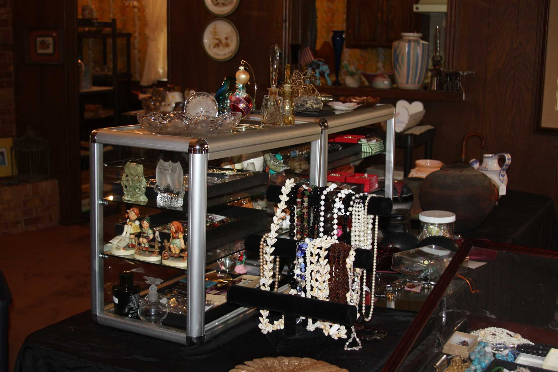 Display case with jewelry and figurines on a black-covered table in a shop.