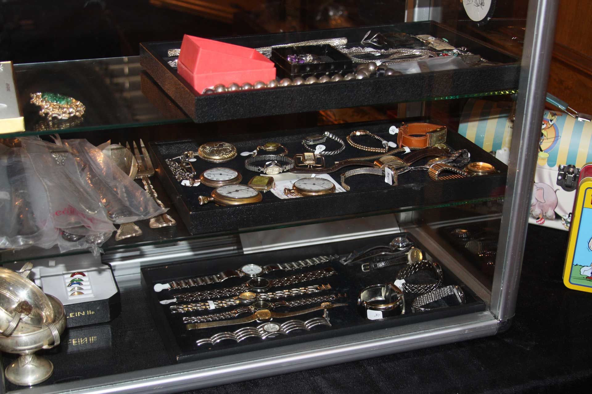 Jewelry display case with various bracelets, watches, and a red box.