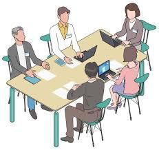 A group of people are sitting around a table with laptops.