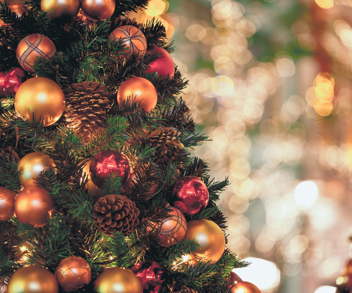 Christmas tree, decorated with gold and red ornaments, pinecones, and lights, blurry background.