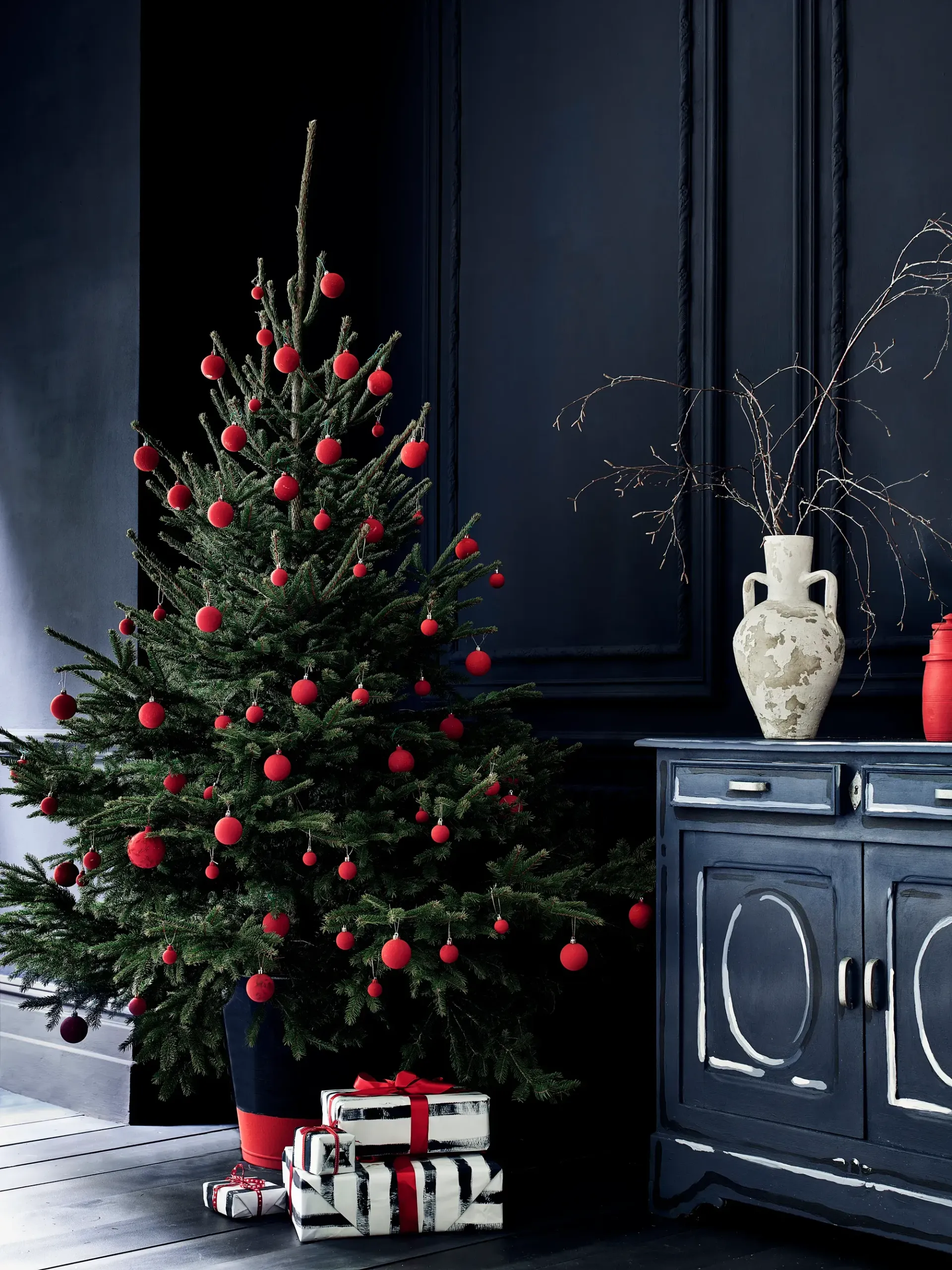 A christmas tree with red ornaments in a dark room A christmas tree with red ornaments in a dark room