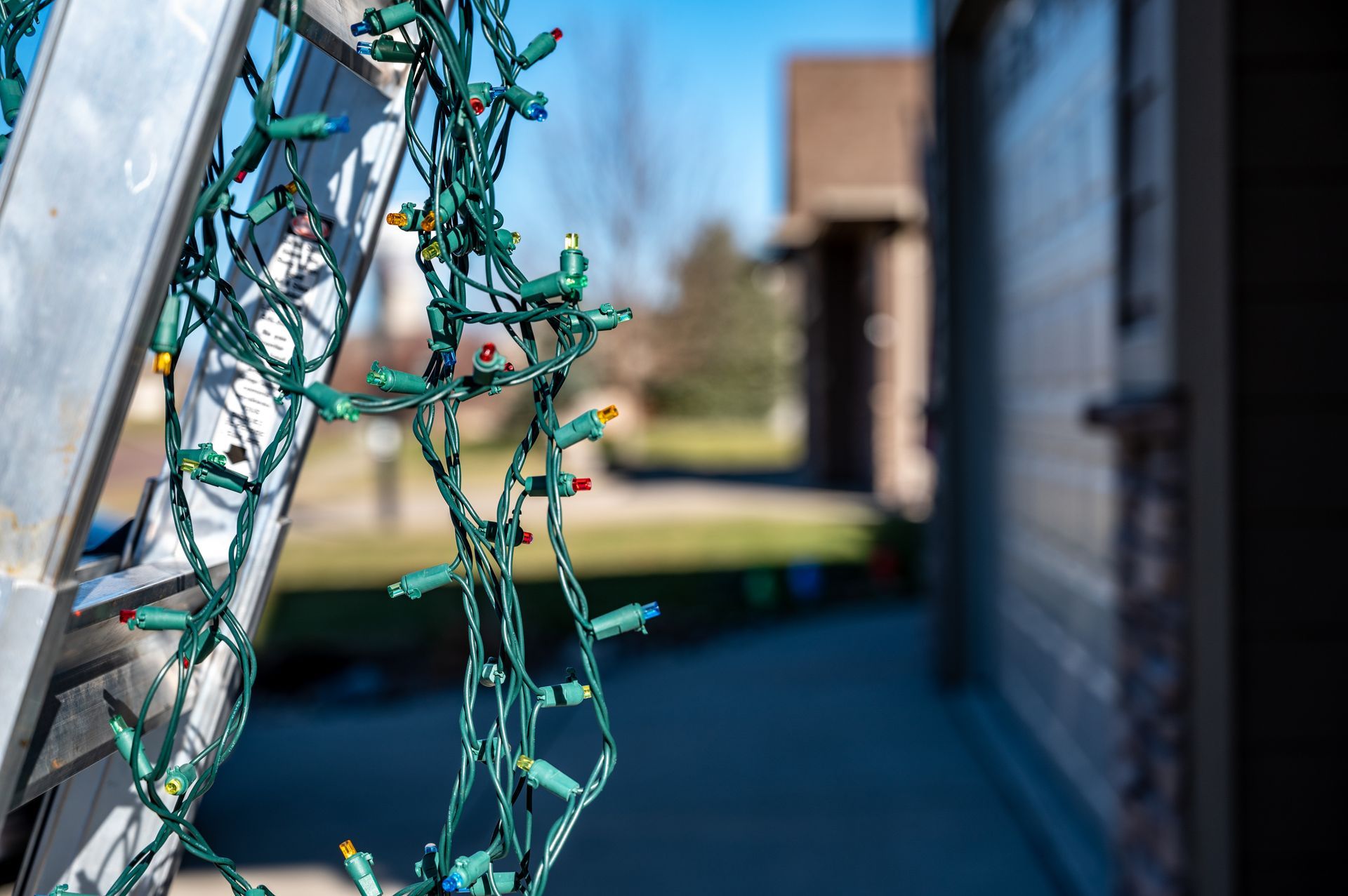 Close-up of green string lights on a porch, with a blurred outdoor building in the background