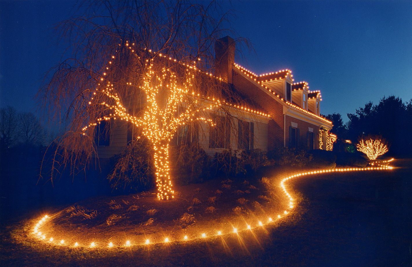 A house decorated with christmas lights is lit up at night by Next Gen Christmas Decor