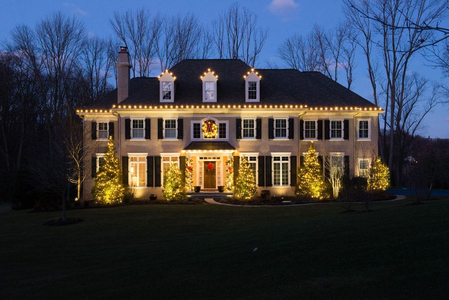 Stone house front door decorated for Christmas with lights, garland, and red bows.