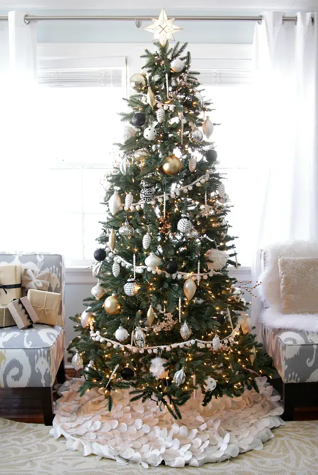 A christmas tree is decorated in gold and white in a living room. A christmas tree is decorated in gold and white in a living room.