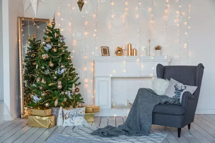A living room decorated for christmas with a christmas tree , fireplace , chair and mirror. A living room decorated for christmas with a christmas tree , fireplace , chair and mirror.