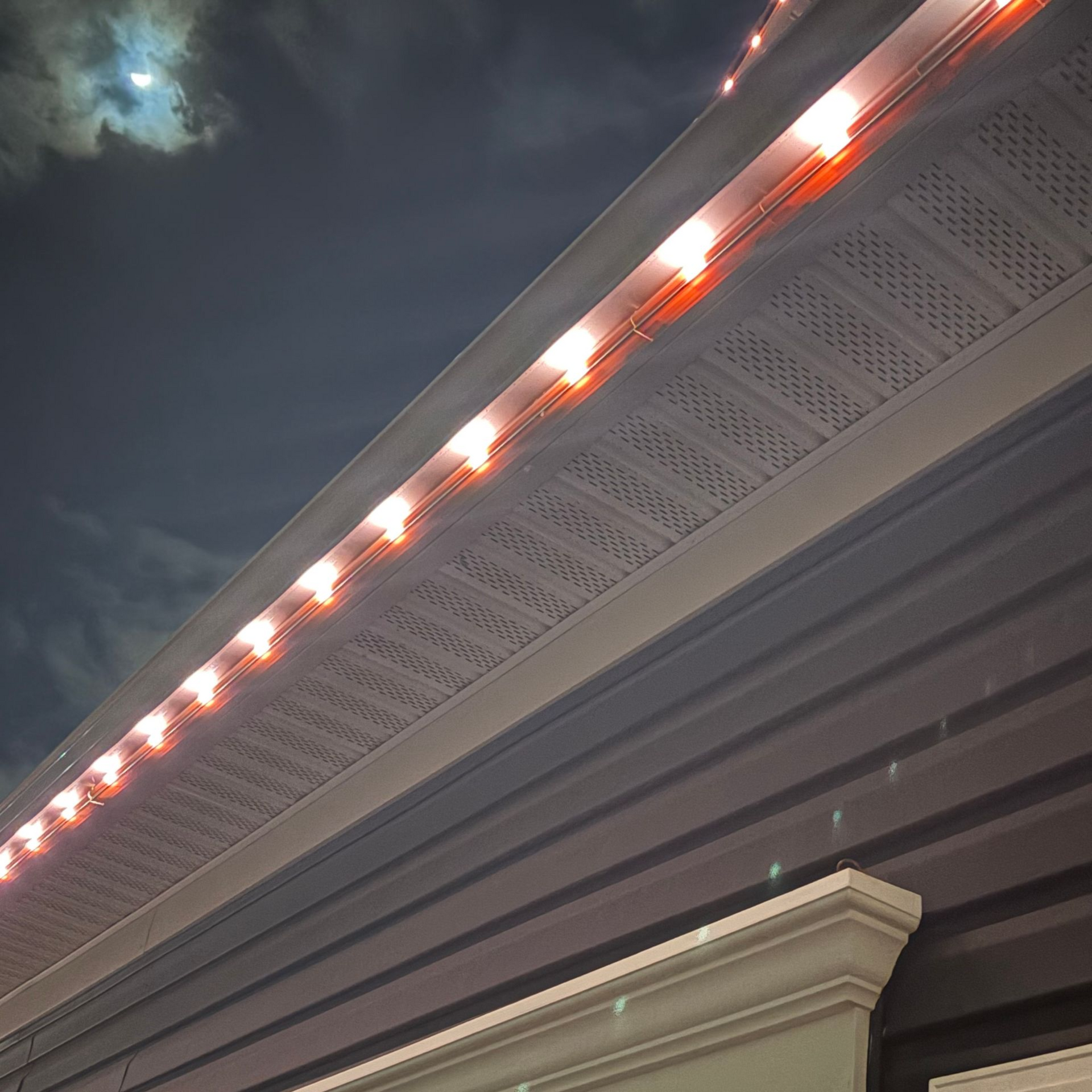 Night sky above a building roofline with glowing orange trim lights