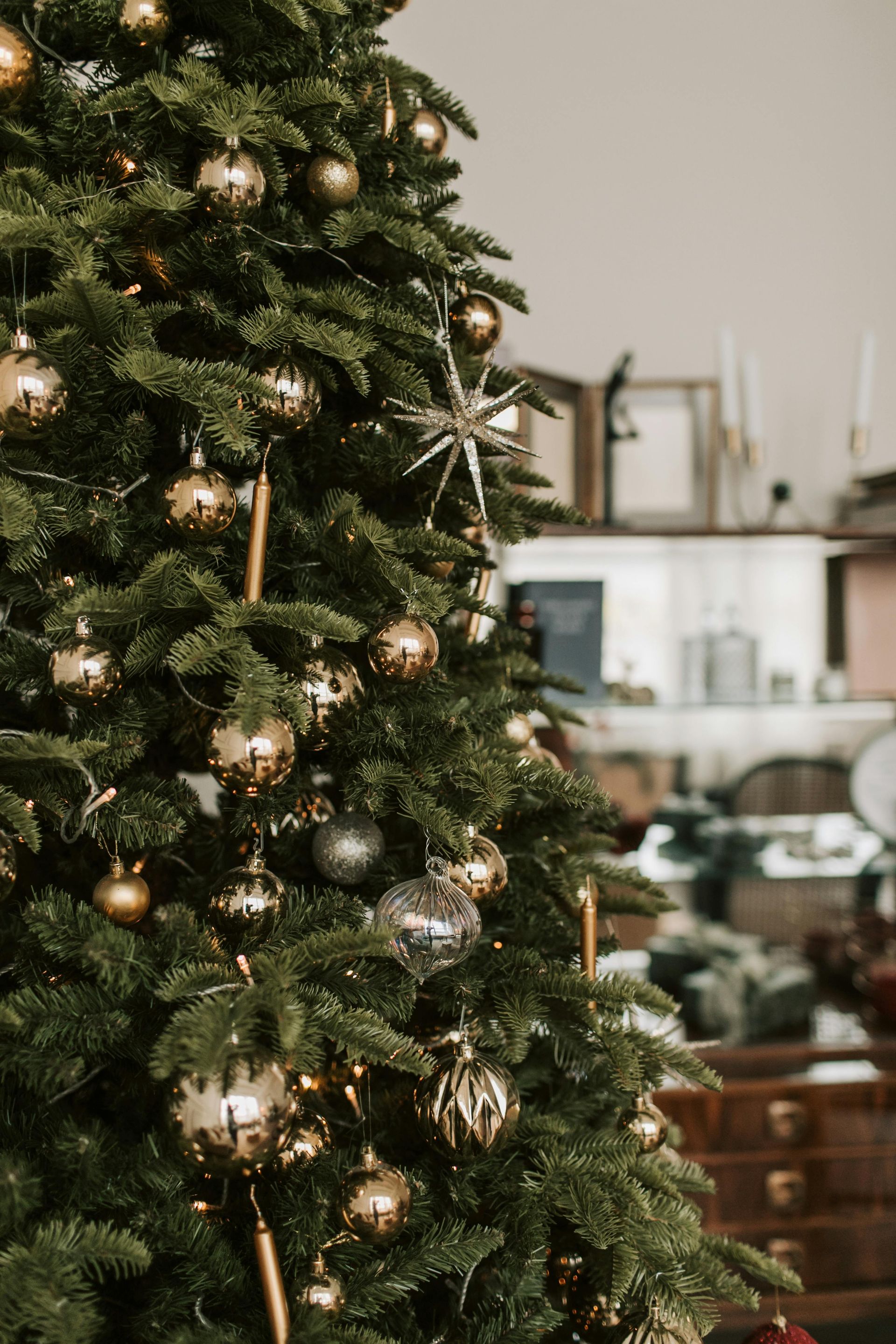 Christmas tree decorated with gold and silver ornaments, in an interior setting.
