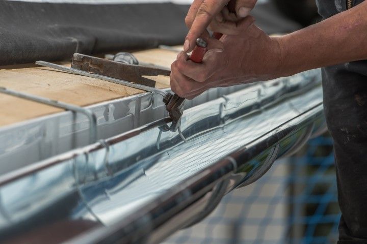 Hands using a tool to work on a boat's fiberglass hull in a workshop