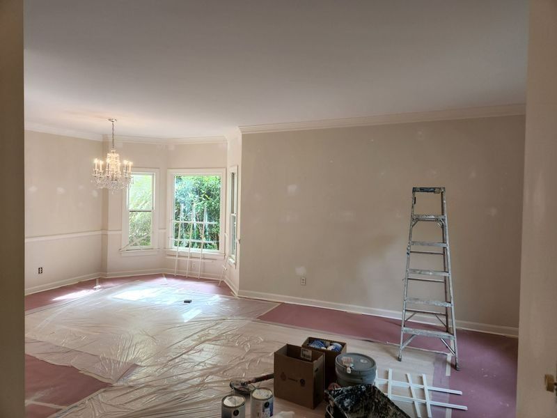 Room being painted, featuring ladder, drop cloths, and painting supplies.