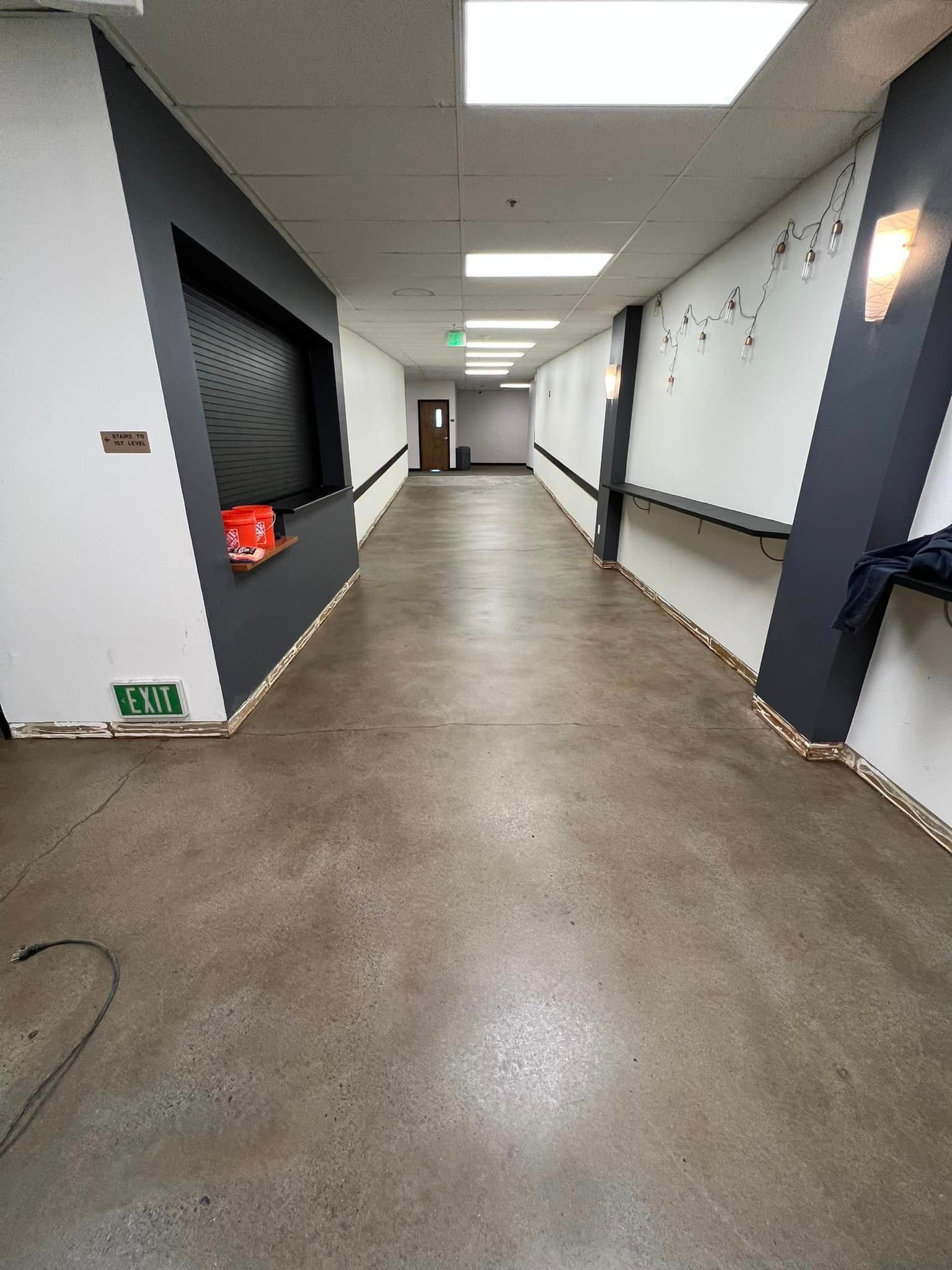 A long hallway with a green exit sign on the wall.