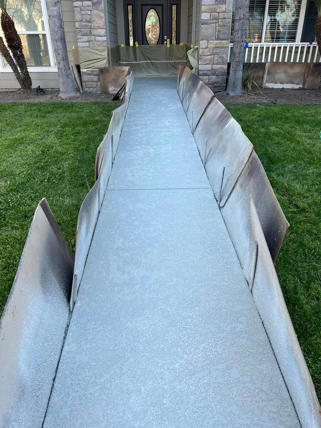 A concrete walkway leading to the front door of a house.