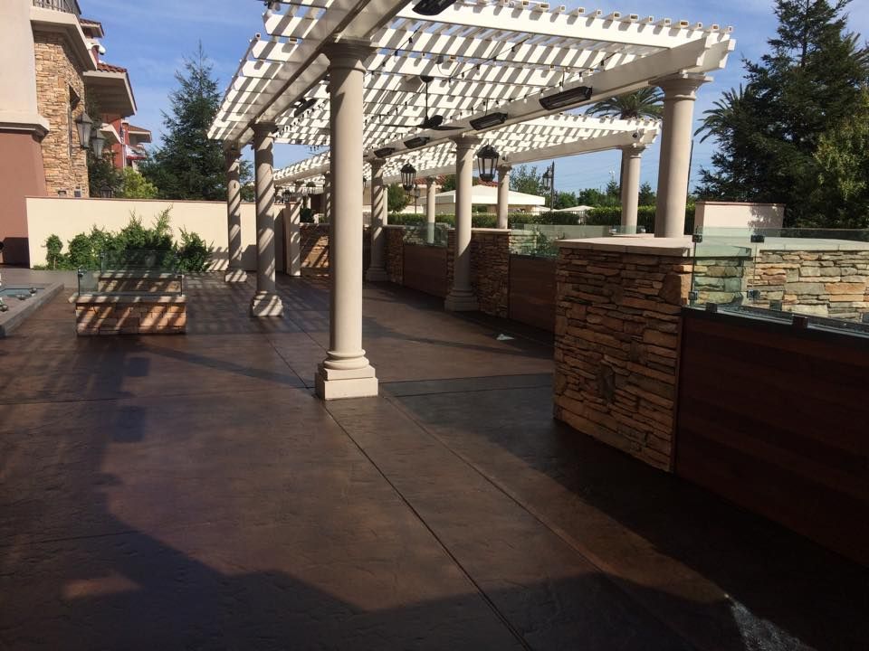 A patio with a pergola and a stone wall