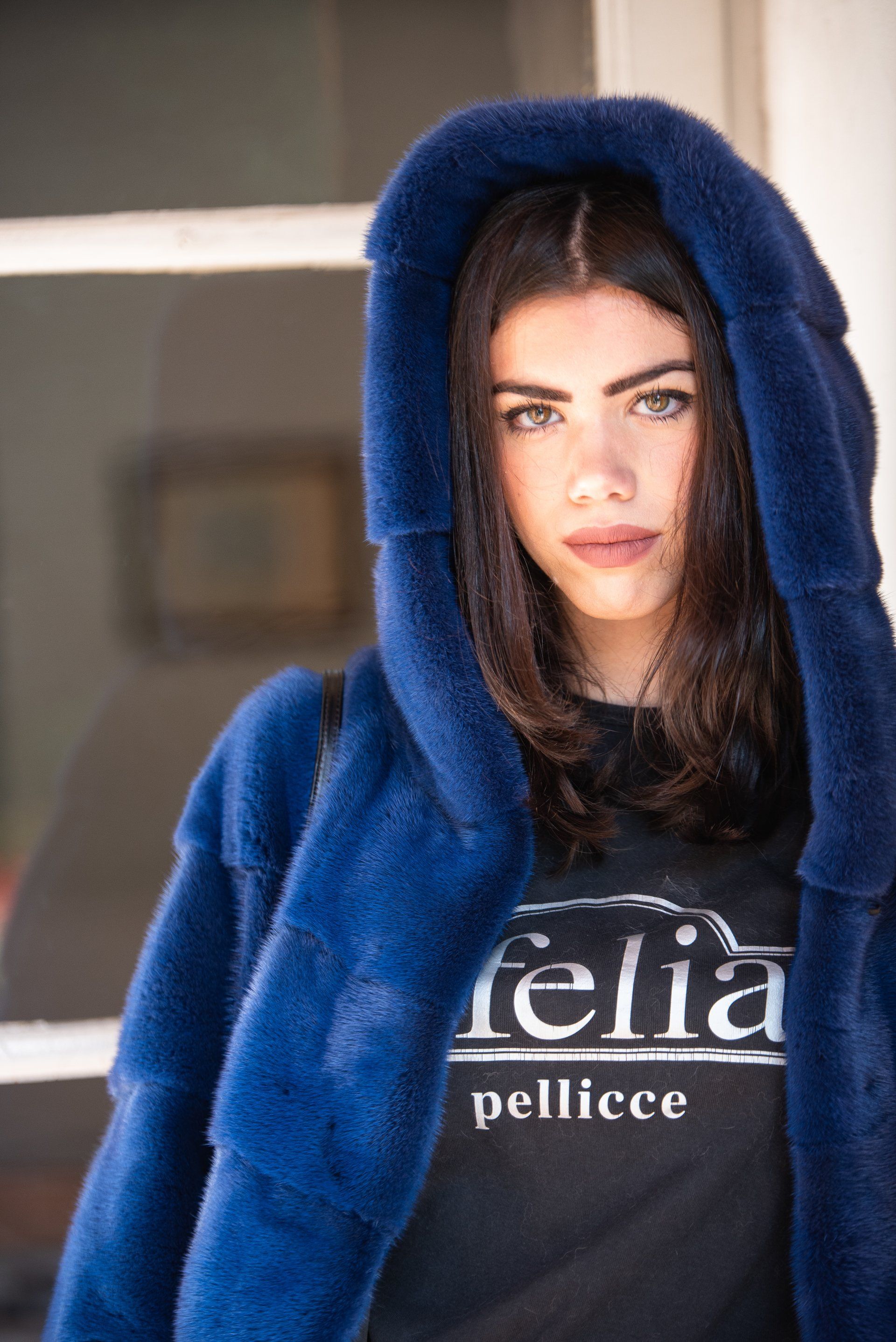 Donna con pelliccia blu con cappuccio, maglietta nera.