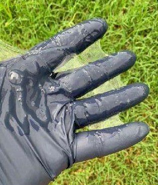 A person wearing a black glove is holding a piece of plastic in their hand.