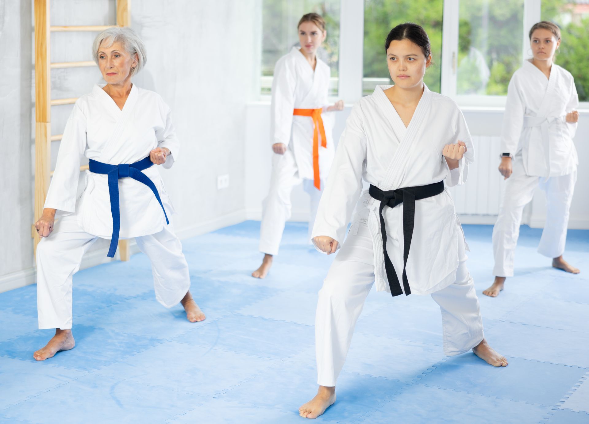 An experienced karate sensei is leading a group of young women during kata training.