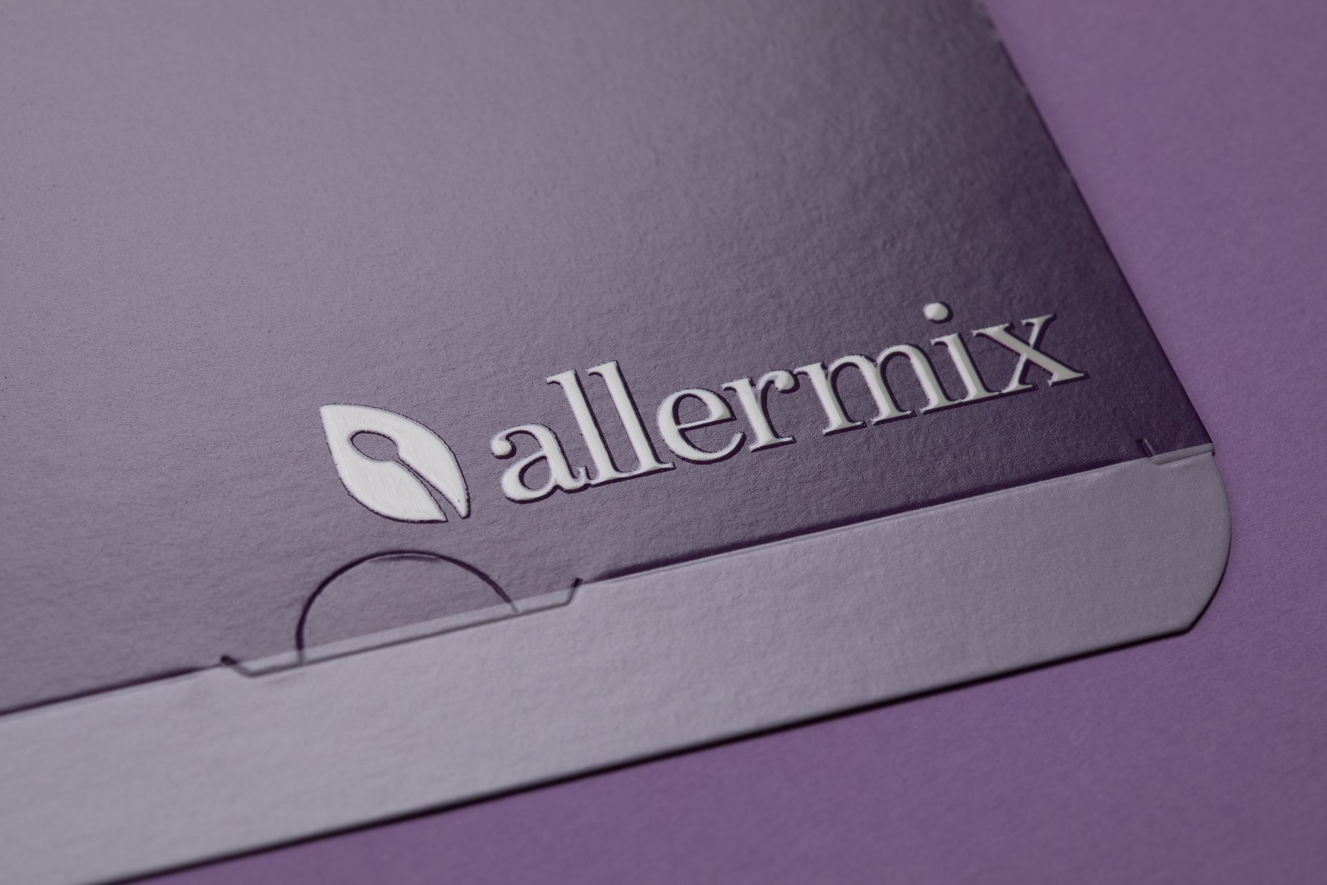 Close-up of a purple Allermix folder or booklet with a silver logo on the corner
