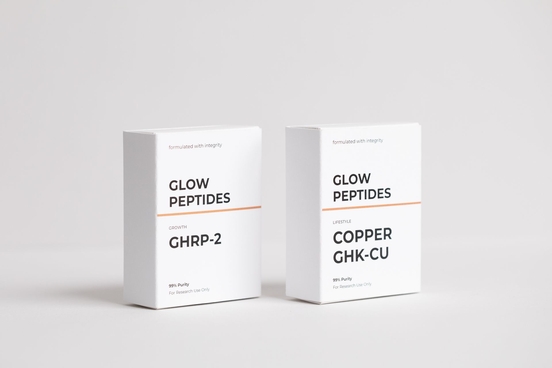 Close-up of white peptide boxes labeled “GLOW PEPTIDES” and “COPPER GHK-CU” on a light surface