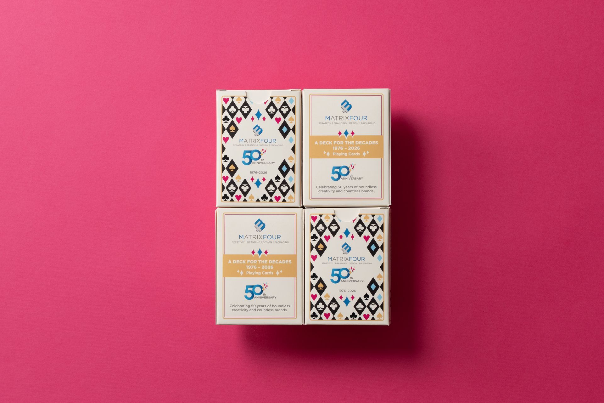 Four small patterned boxes arranged in a square on a bright pink background