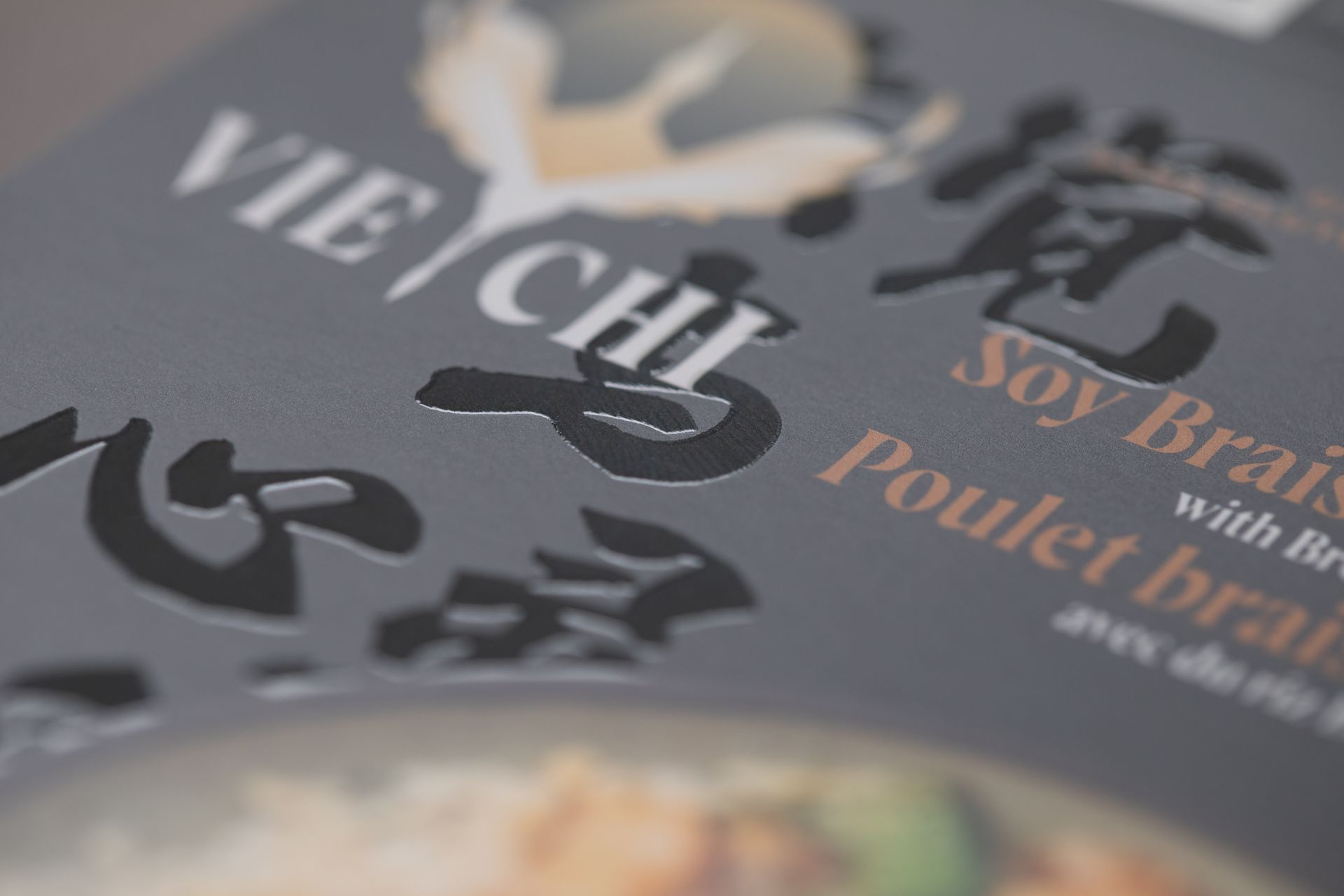 Close-up of food packaging with Vietnamese dishes and blurred food photos on a grey background