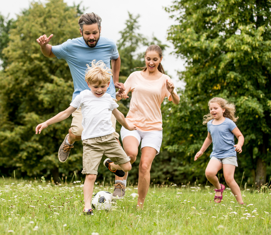 A family is playing with a soccer ball in a park.