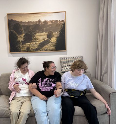 Woman holding two young adults with disabilities