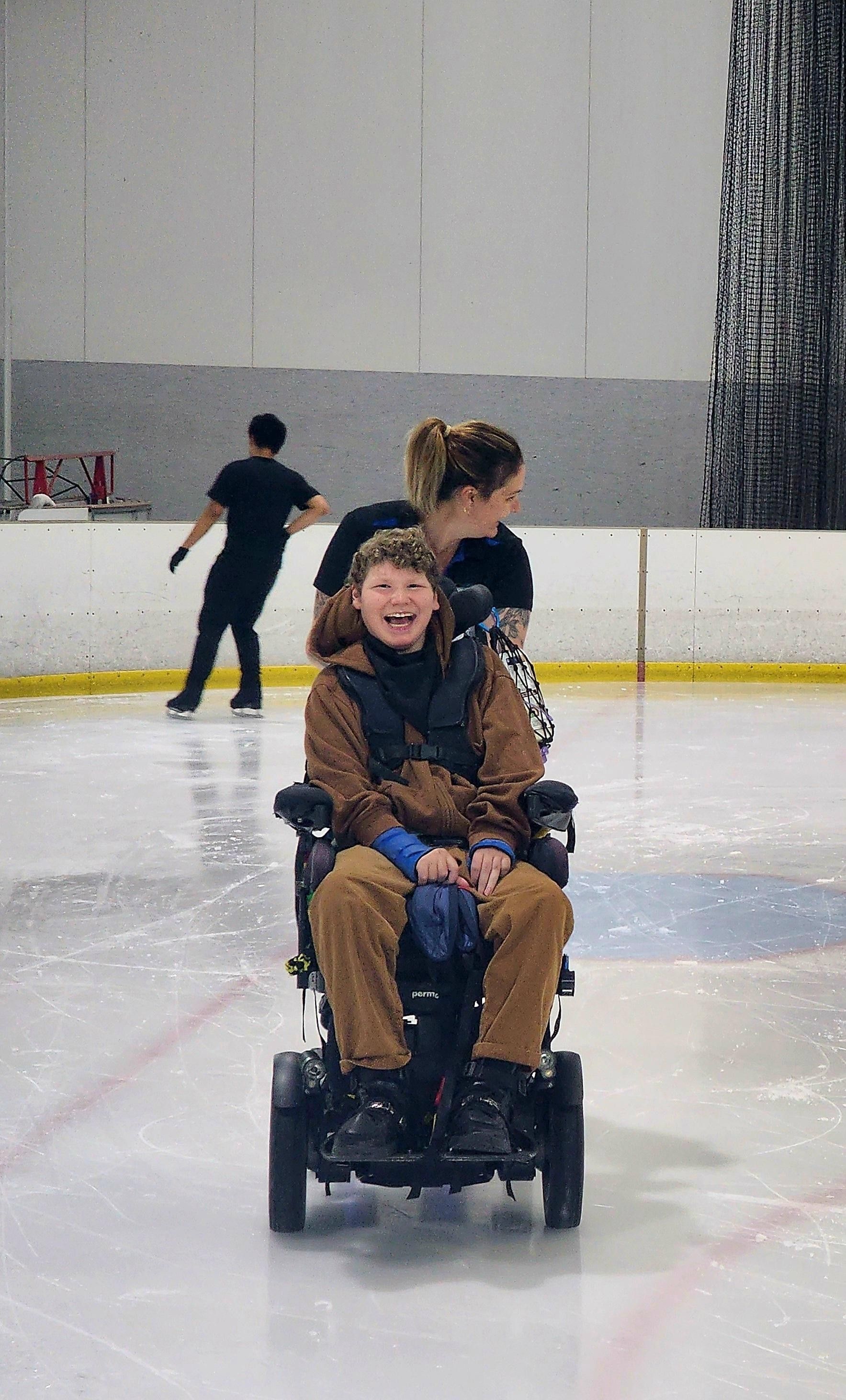A young man in a wheelchair is being pushed on ice