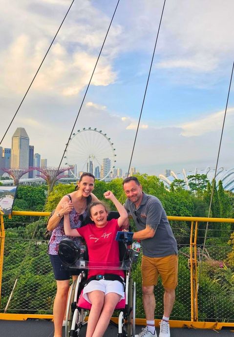 A group of people are standing on a walking platform in Singapore.