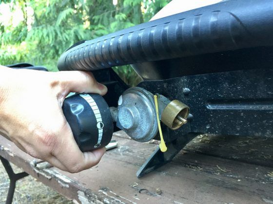 A person is adjusting a gas valve on a grill