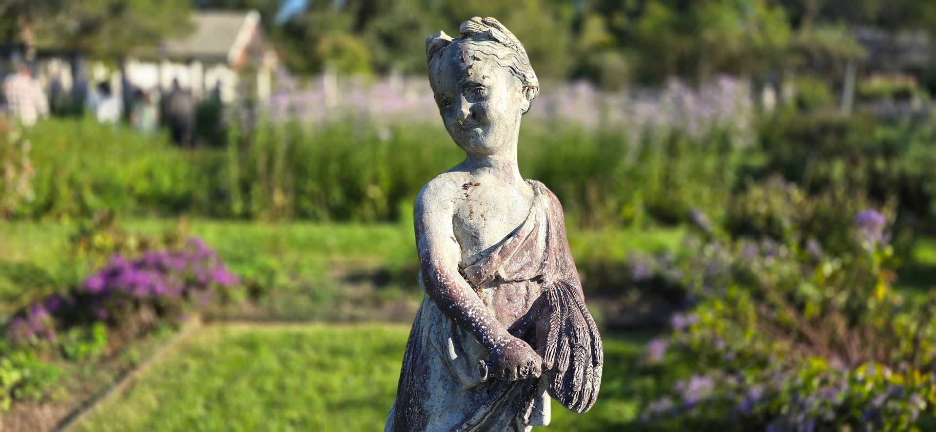 A statue of a woman holding a basket of flowers in a garden.