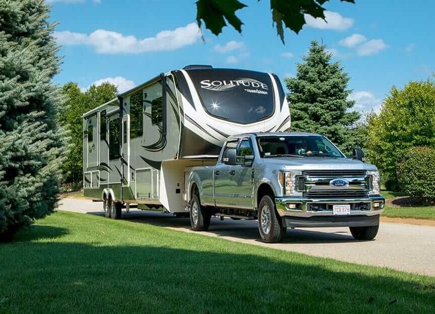 A truck is towing a rv down a road.