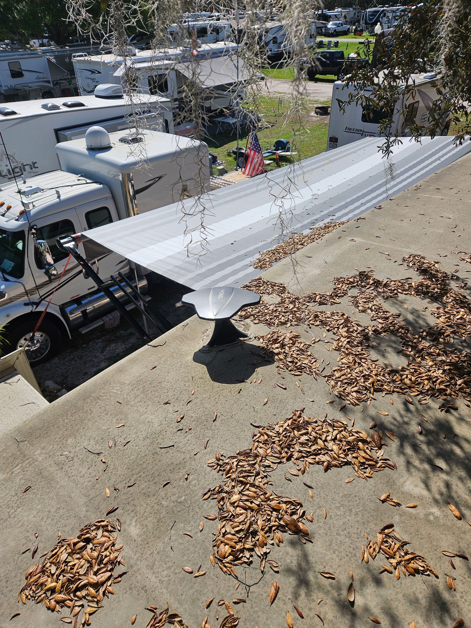 White corrugated roof panel on a rooftop, with trucks, trees, and a yard below in bright sunlight