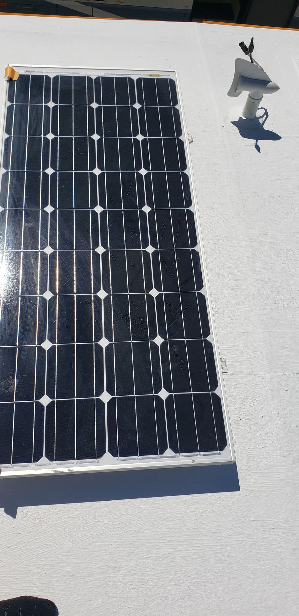 Black solar panel on a white surface with two small gray bird figurines nearby.