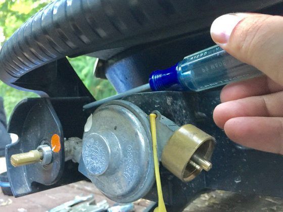 A person is holding a screwdriver next to a gas valve