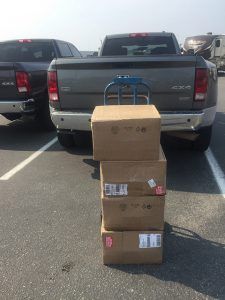 A stack of boxes is sitting in front of a truck in a parking lot.