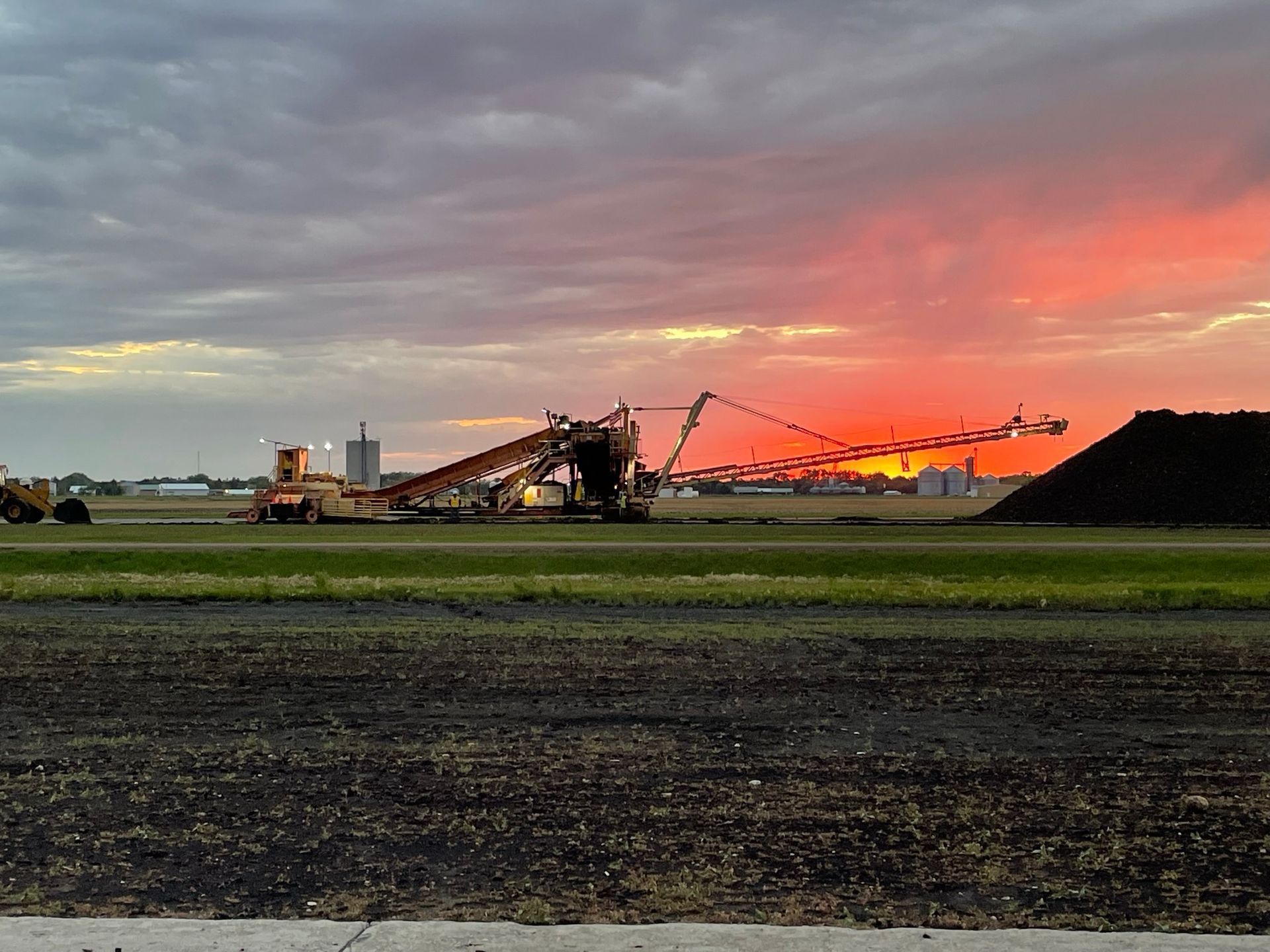 A large pile of dirt is sitting in the middle of a field at sunset.