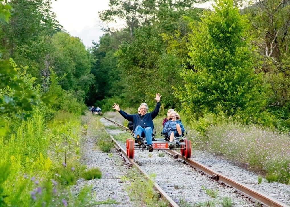 A group of people are riding a go kart on train tracks.