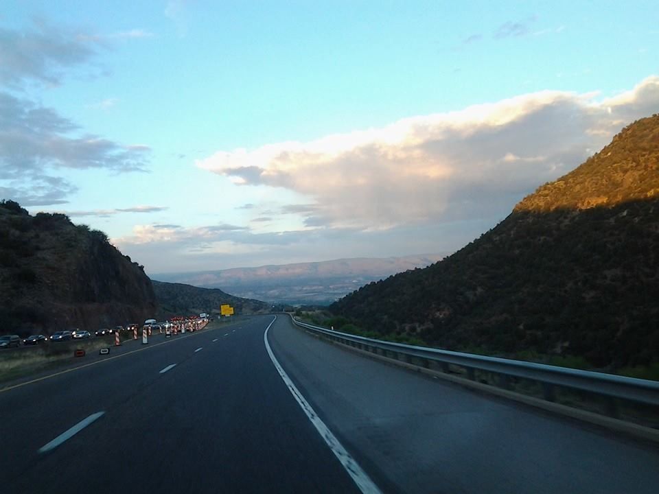 Highway winding through mountains, under a cloudy sky.