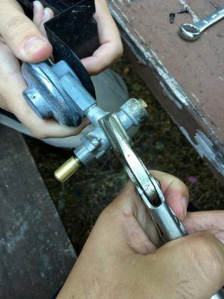 A person is working on a piece of metal with a wrench.