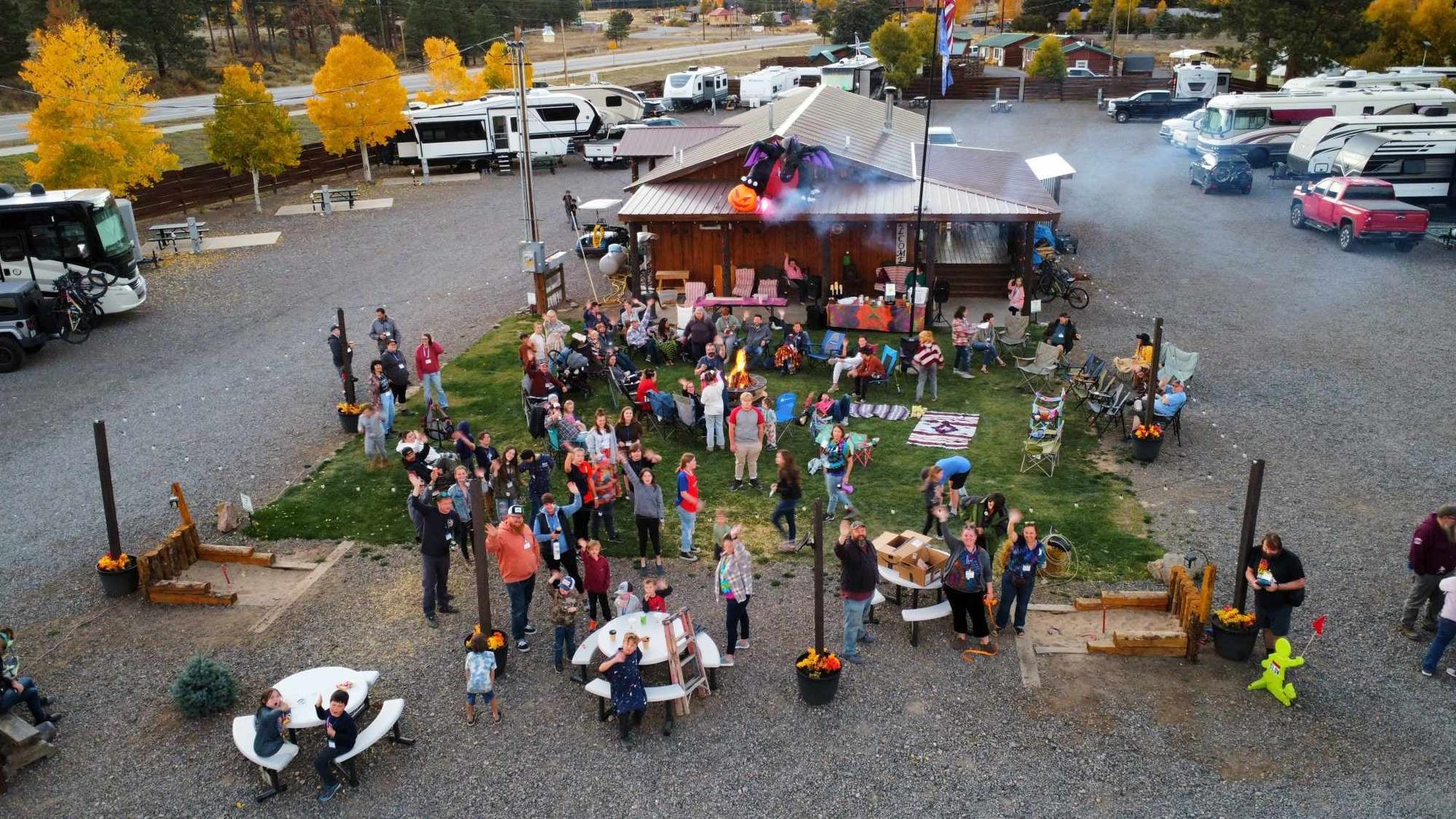 An aerial view of a group of people sitting at picnic tables in front of a building.